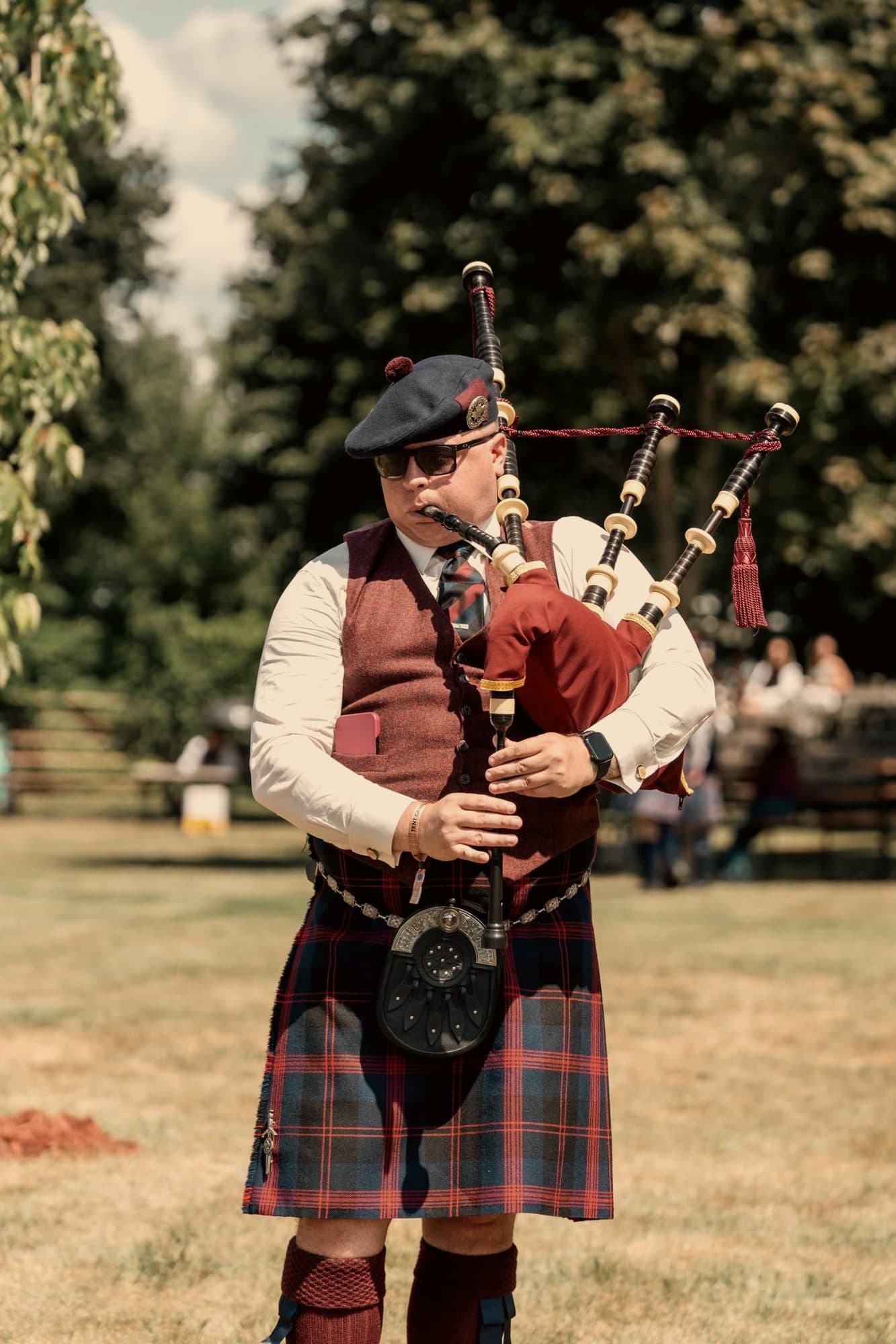 A piper in full dress playing in an open field