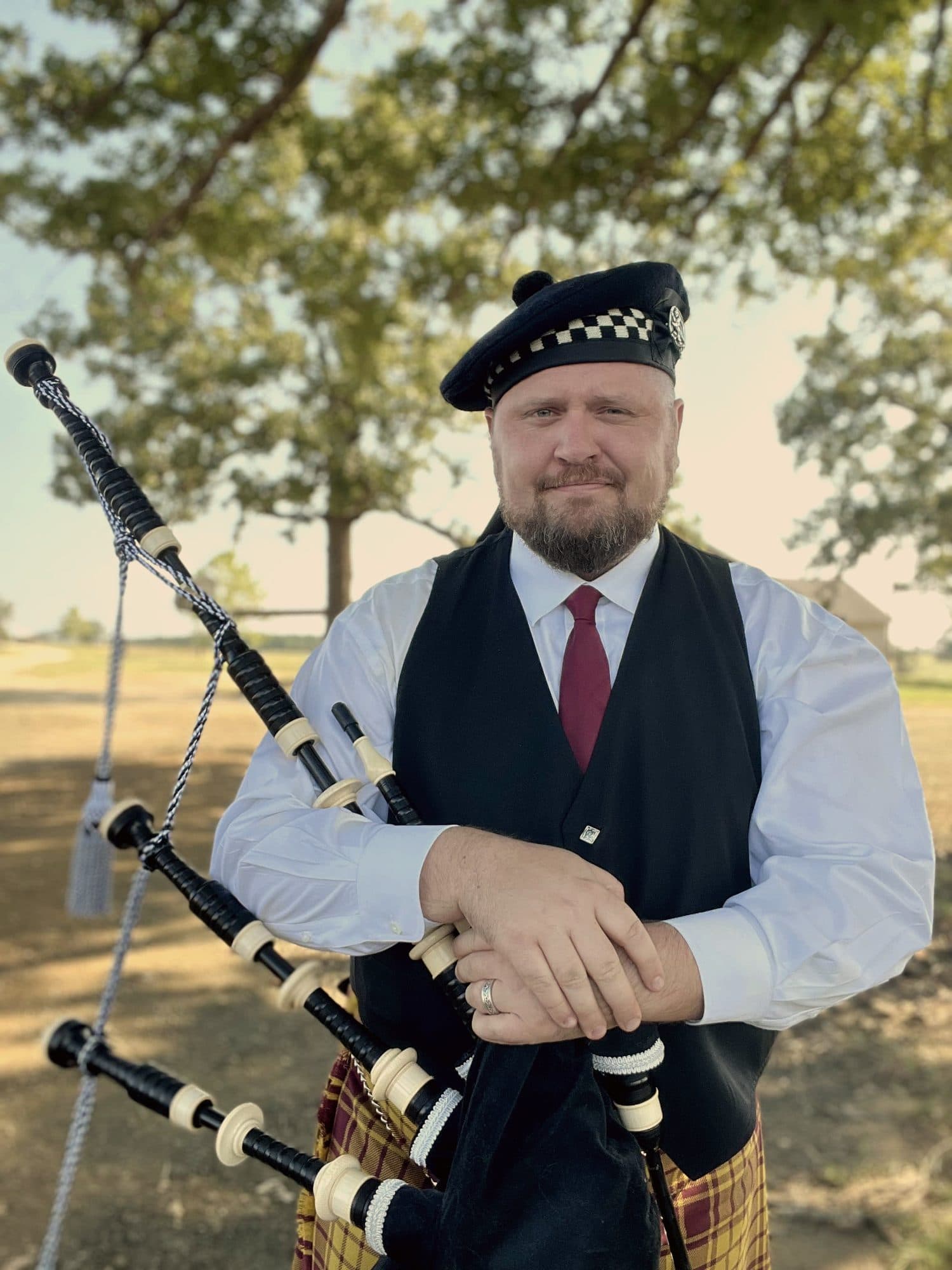 A piper in waistcoat and tie holding his pipes
